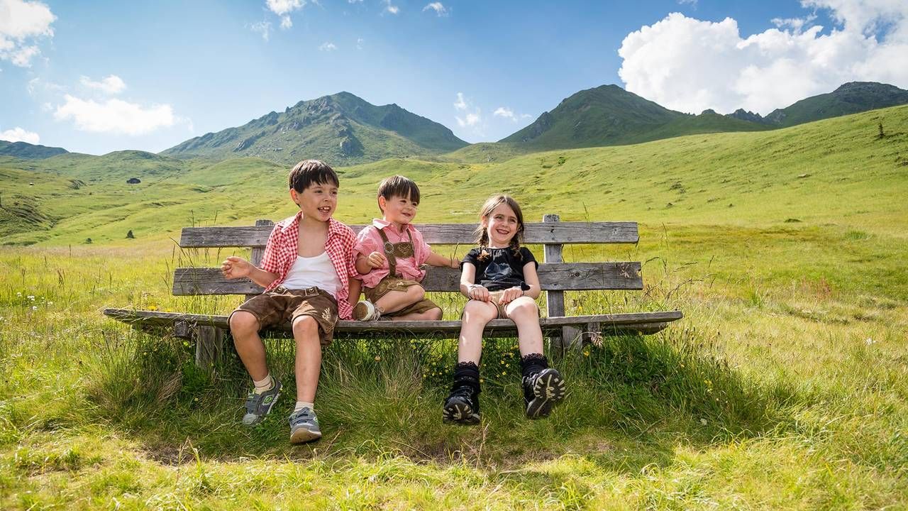 Kinder sitzen auf einer Bank auf der Alm im Gsiesertal